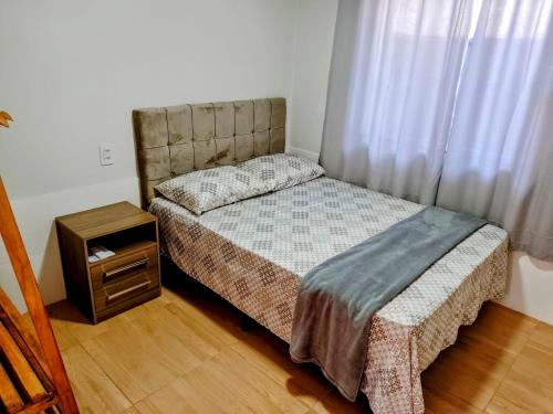 Habitación pequeña con cama y mesita de noche en CASA DE ALUGUEL VÓ DUMA, en Penha