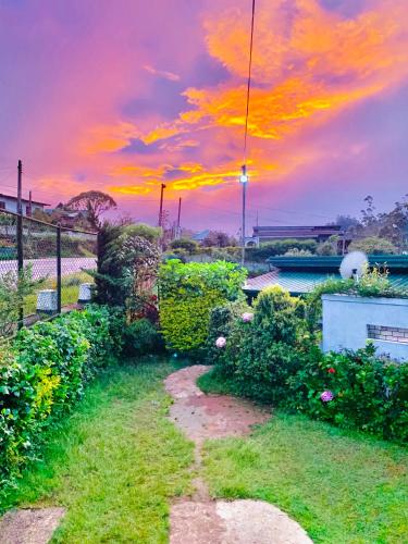 a garden with a sunset in the background at Miliya Guest House in Nuwara Eliya