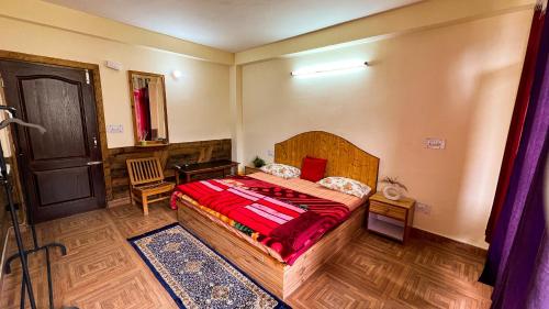 a bedroom with a bed and a desk and a door at YOLO Backpackers MAX - Manali in Manāli