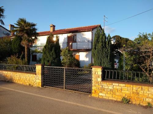une maison avec une clôture et des arbres devant elle dans l'établissement Adriana Holiday house Nova Vas, à Nova Vas