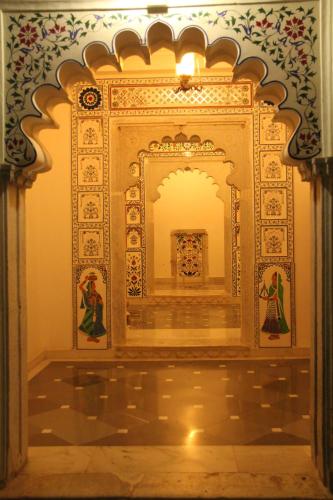 an ornate room with a wall with paintings on it at Sardargarh Heritage Fort Udaipur in Sardārgarh
