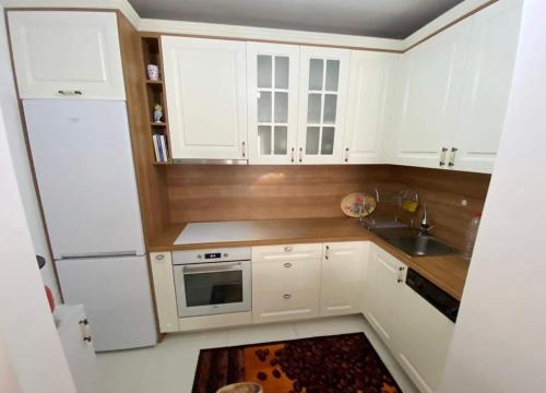 1-Bedroom Apartment Fushë Kosovë في Kosovo Polje: مطبخ صغير مع دواليب بيضاء ومغسلة