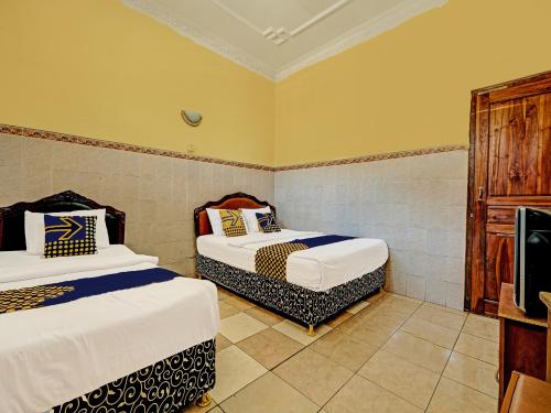 1 dormitorio con 2 camas y TV. en OYO Life 91677 Hotel Citra Dewi 3, en Semarang