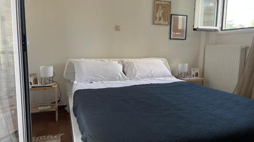 1 dormitorio con 1 cama con manta azul y almohadas blancas en Athens Taratsaki, en Atenas