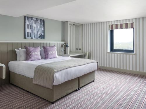 1 dormitorio con 1 cama grande con almohadas moradas en Village Hotel Aberdeen, en Aberdeen