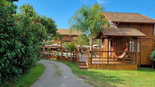 uma cabana de madeira com uma cerca ao lado de uma estrada em Arte da Tribo Hostel & Camping na Praia do Rosa