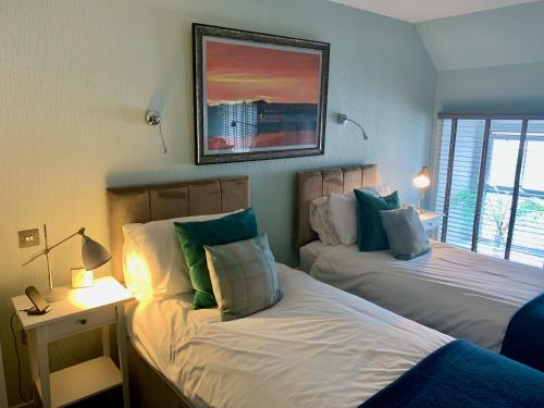 a bedroom with two beds and a picture on the wall at Lochindaal Hotel in Port Charlotte