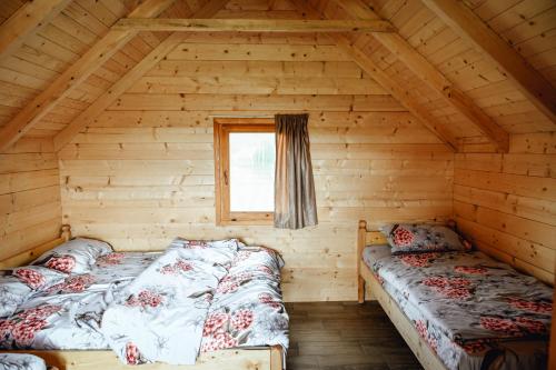 two beds in a log cabin with a window at Vidikovac Uvac in Družiniće