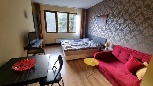 Una sala de estar con un sofá rojo y una cama. en Borovets Hills Apartments - Studio 33, en Borovets