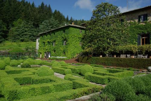 a garden in front of a building with bushes at Badia a Coltibuono Wine Resort in Gaiole in Chianti