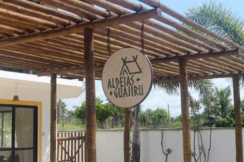 a wooden pergola with a sign hanging from it at Aldeias Guajiru Apart in Trairi