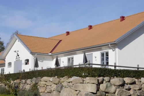 a white house with a red roof and a stone wall at STF Andrarum Kuskahusen Hostel in Andrarum-Brosarp