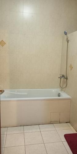 a white bath tub in a bathroom with a tile floor at L'Address in Cotonou