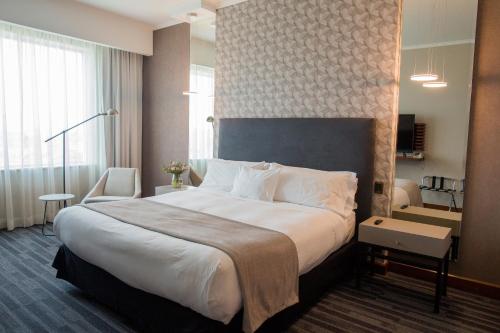 a hotel room with a large bed with white sheets at MDS Hotel Concepción in Concepción