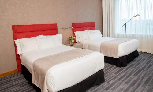a hotel room with two beds with red headboards at MDS Hotel Concepción in Concepción