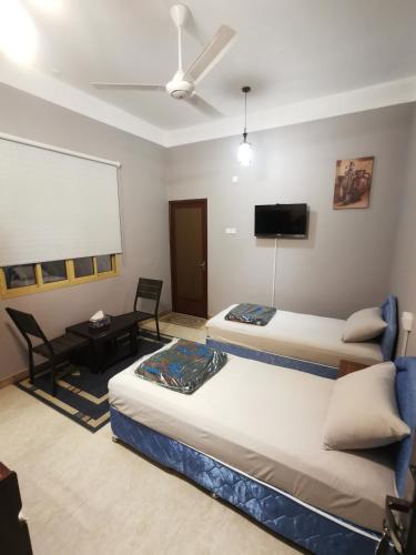 a room with two beds and a flat screen tv at Al Hamra Guest House in Al Ḩamrāʼ