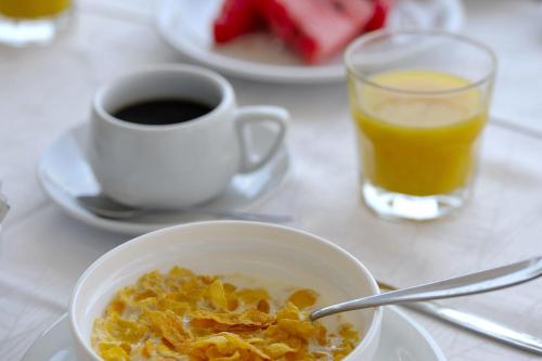 a bowl of cereal and a glass of orange juice at Esperia Hotel in Kavala