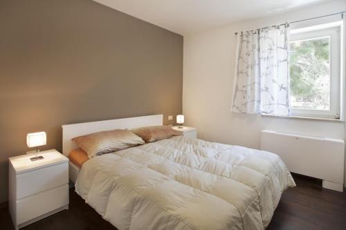 sypialnia z dużym białym łóżkiem i oknem w obiekcie Casa M Rabac w Rabacu
