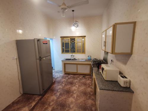 a kitchen with a refrigerator and a sink at Al Hamra Guest House in Al Ḩamrāʼ