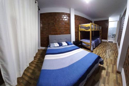 een slaapkamer met een blauw en wit bed en een bakstenen muur bij CASA PLAYA REFUGIO AZUL in Cerro Azul