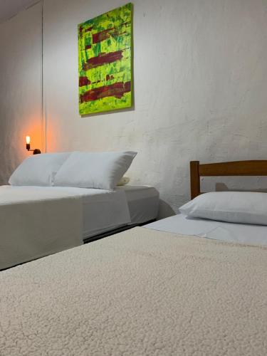 two beds in a bedroom with a painting on the wall at Bendita Pausa-Igatu in Igatu