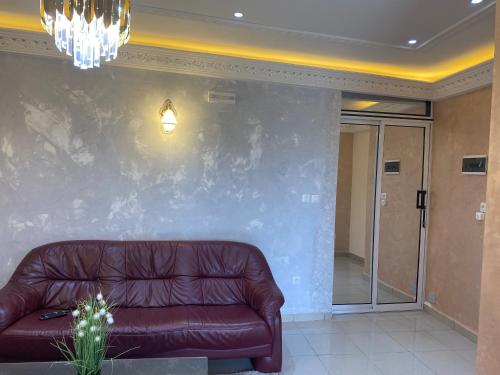 a brown leather couch in a room with a wall at RÉSIDENCE MARTHA in Yaoundé