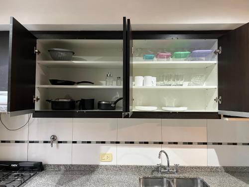 a kitchen with black and white cabinets with dishes at Hermoso duplex con estacionamiento in Guaymallen