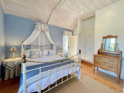 a bedroom with a canopy bed with a wooden ceiling at Praze Cottage in Cardinham