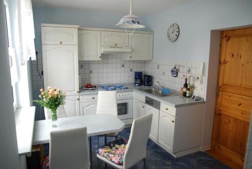 una cocina con armarios blancos y una mesa con sillas. en Ferienwohnung Burgruine, en Rauenstein