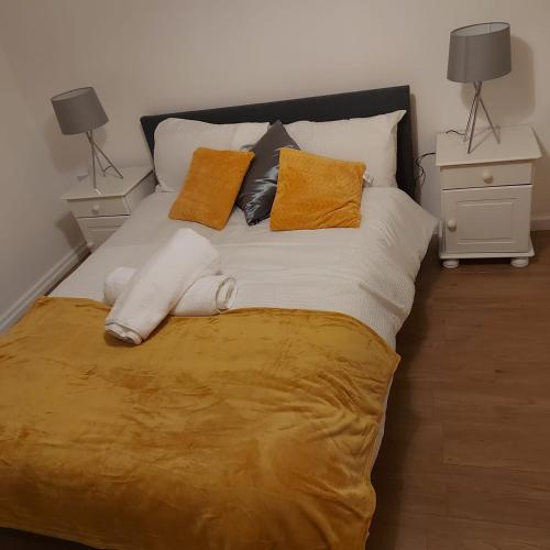 a bed with orange and white pillows on it at Lovely 2-Bed Apartment in Milton Keynes in Milton Keynes