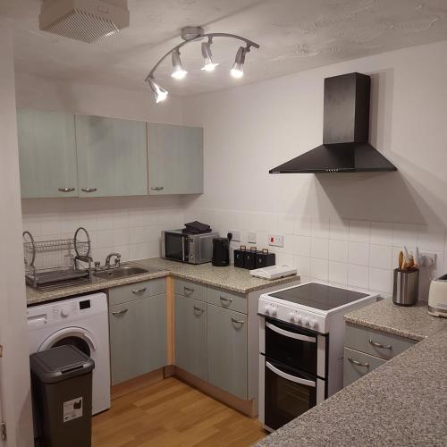 a kitchen with white cabinets and a stove top oven at Lovely 2-Bed Apartment in Milton Keynes in Milton Keynes