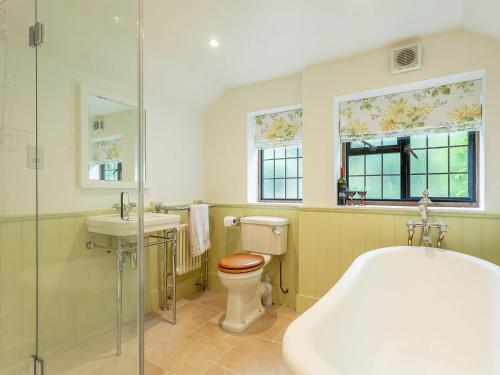 a bathroom with a tub and a toilet and a sink at Pollard Cottage in Lingfield