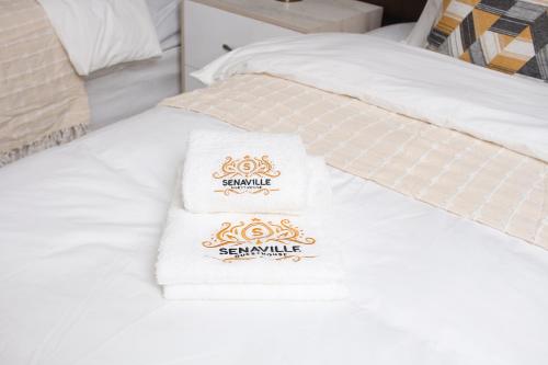 two towels sitting on top of a white bed at Senaville Guesthouse in Louis Trichardt