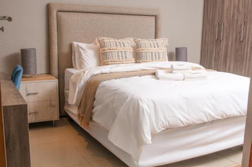 a bedroom with a large bed with white sheets and pillows at Senaville Guesthouse in Louis Trichardt