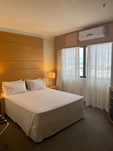 una camera da letto con un grande letto bianco e una finestra di Lindo Flat ao Lado do Aeroporto de Congonhas a San Paolo