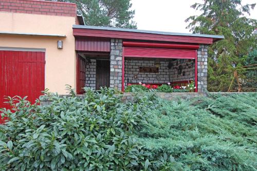 a red building with a red door and some bushes at Ferienhaeuser Zinnowitz USE 1760 in Zinnowitz