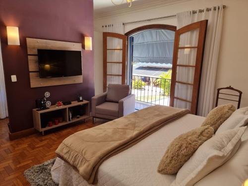 a bedroom with a bed and a television and a chair at Saison Resort & Spa in Itaipava