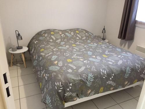 - un lit avec une couette noire et un motif végétal dans l'établissement Appartement offrant une magnifique vue des montagnes, à Saint-Léger-les-Mélèzes