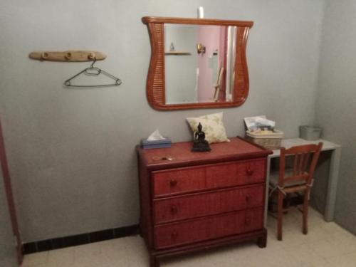 eine Kommode mit einem Spiegel und einem Stuhl in einem Zimmer in der Unterkunft Chambre chez l'habitant in Pierrelatte