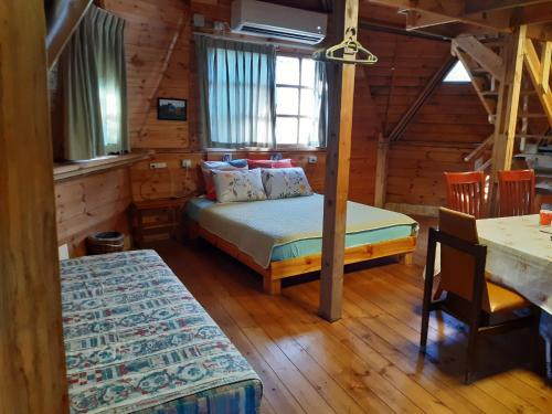 1 dormitorio con 1 cama en una cabaña de madera en בקתת עץ בחורש במנות - דום גיאודזי - Wooden cabin in Manot en Manot