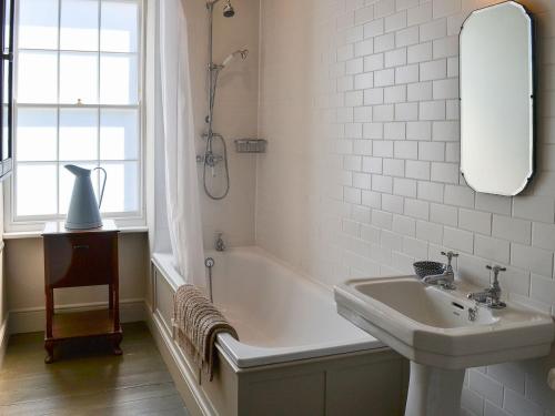 a bathroom with a tub and a sink and a mirror at Blackbird House in Alnwick