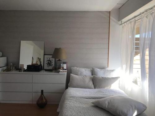 Un dormitorio con una cama con almohadas blancas y una ventana en HeberGeneve : Balcon sur le Jura, en Gex