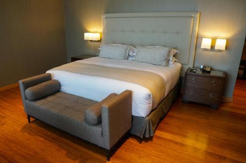 a bedroom with a large bed and a chair at Hotel Parada Linares in Linares