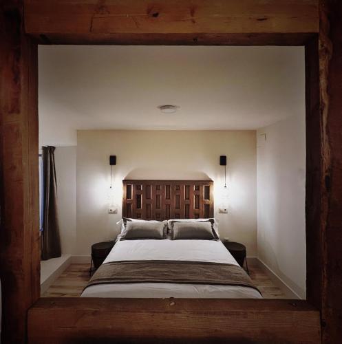 a bedroom with a large bed with a wooden headboard at Casa de las Lías in Chinchón