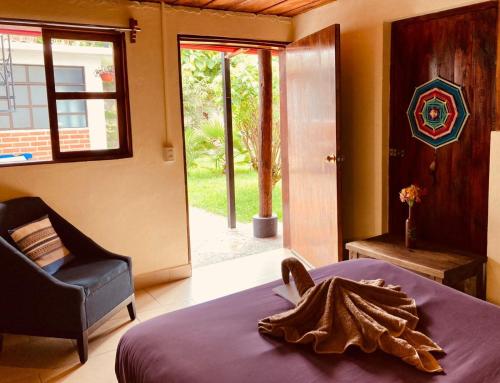 um quarto com uma cama, uma cadeira e uma janela em Casa Flor de Vida em San Cristóbal de Las Casas