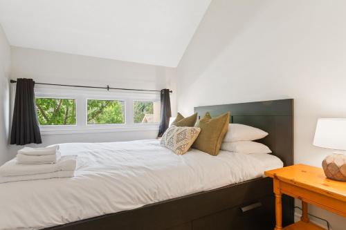 1 dormitorio con cama con almohadas y ventana en Lovely 3 Bedroom Wintergreen Retreat w Sauna, en Blue Mountains
