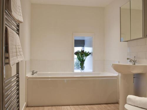 a bathroom with a tub and a vase of flowers in a window at Thistle Cottage in Carlton