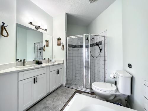 a white bathroom with a shower and a toilet at Glenbrook Pool Lake Home in Orlando