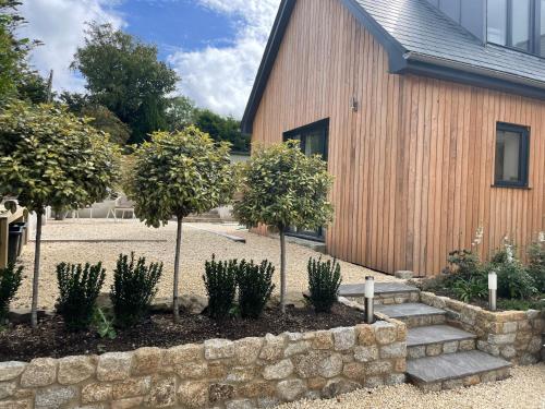a stone retaining wall next to a building with trees at Cedar House in Ilsington