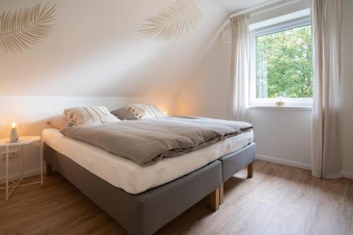 a bed in a white room with a window at Moderne Küstenbutze #1 im Beach-Style in Mildstedt